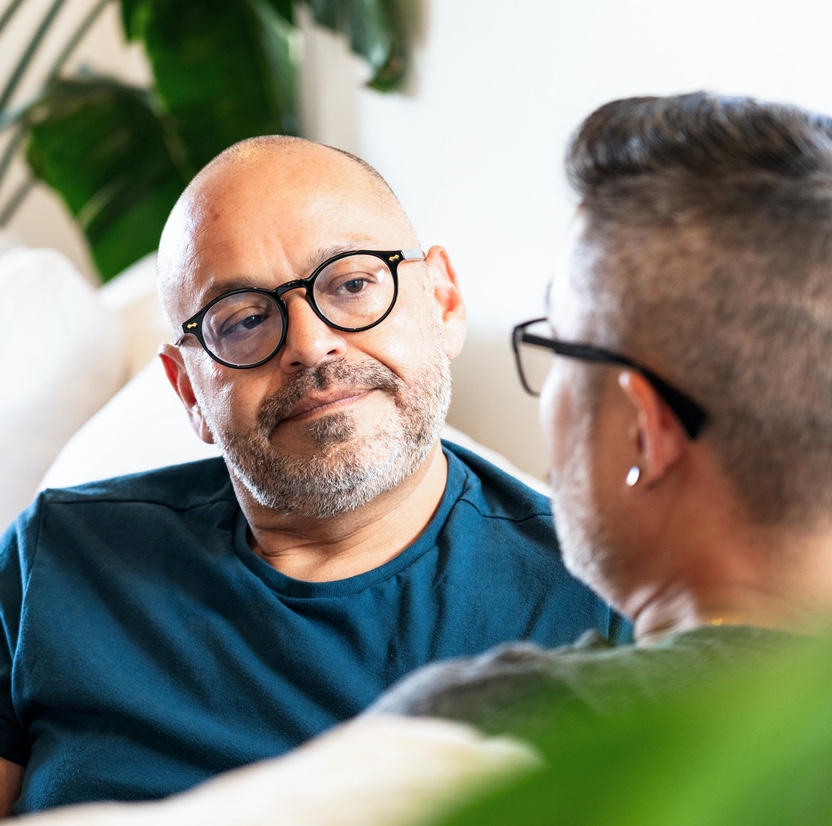 Man listening intentently to another person while seated on a couch